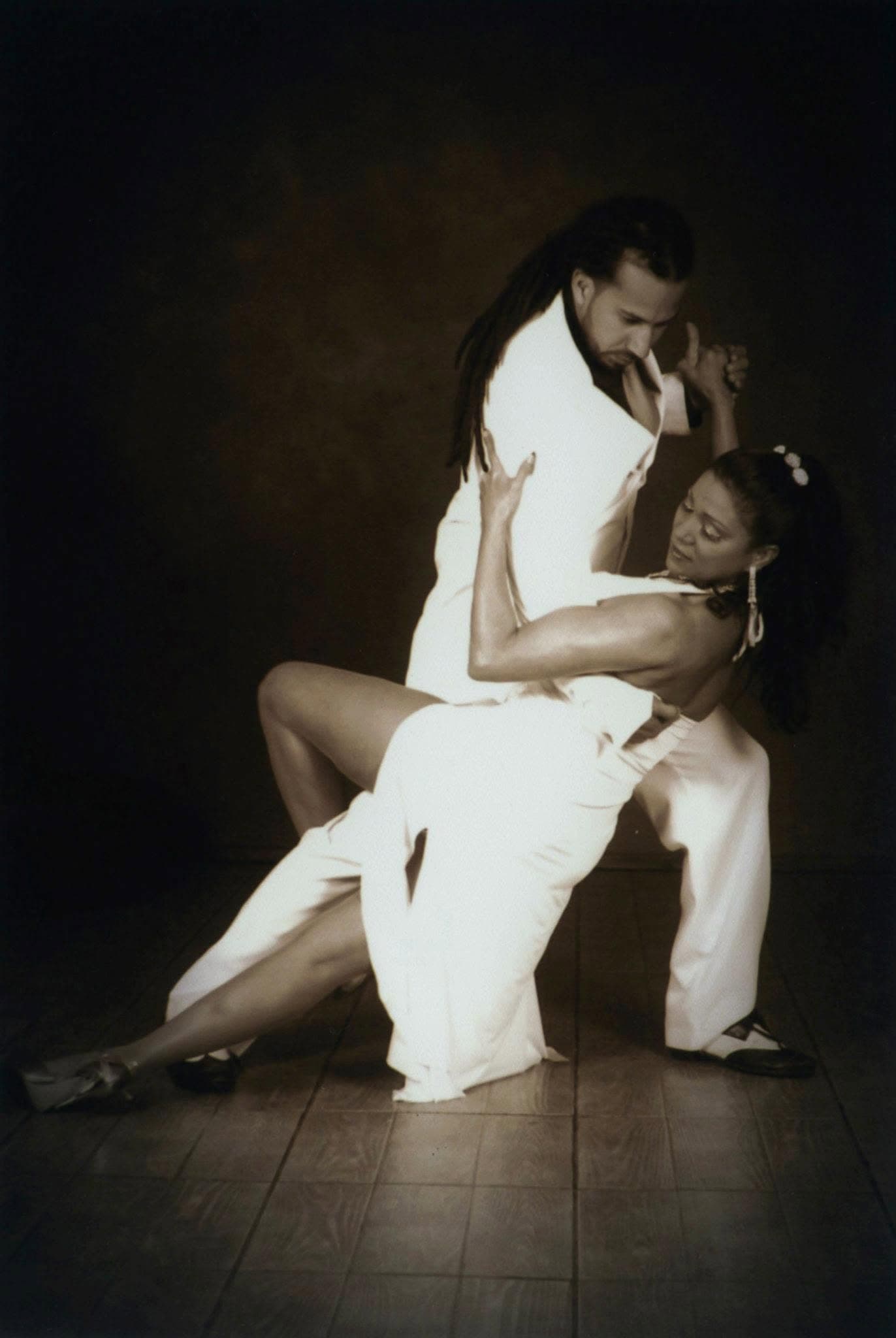 Alexis Andrade en pose de tango de estudio, traje blanco