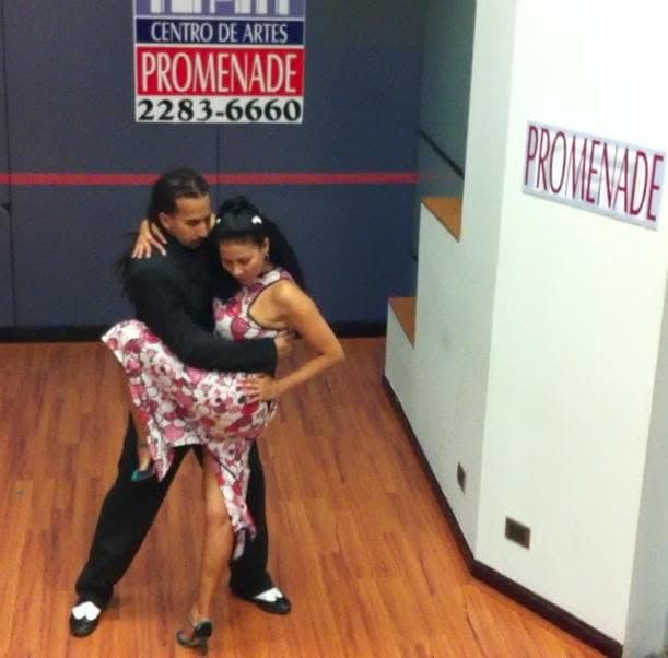 Alexis Andrade bailando tango en un salón, vestido de flores