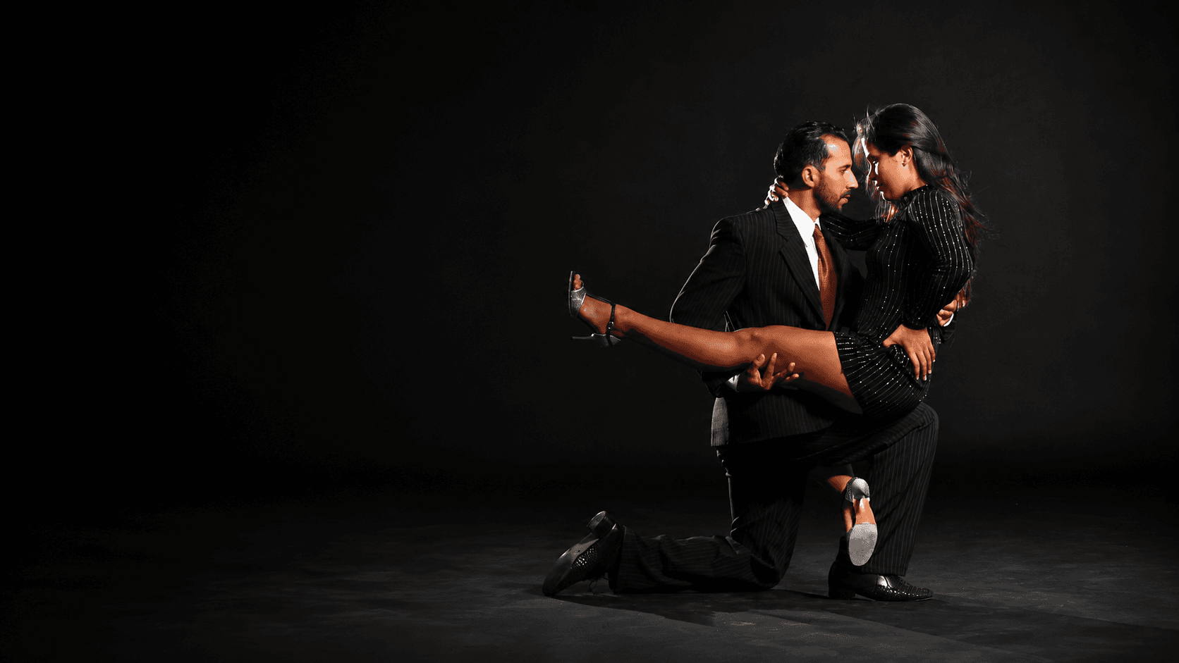Pareja de tango en un abrazo profundo con la pierna en alto