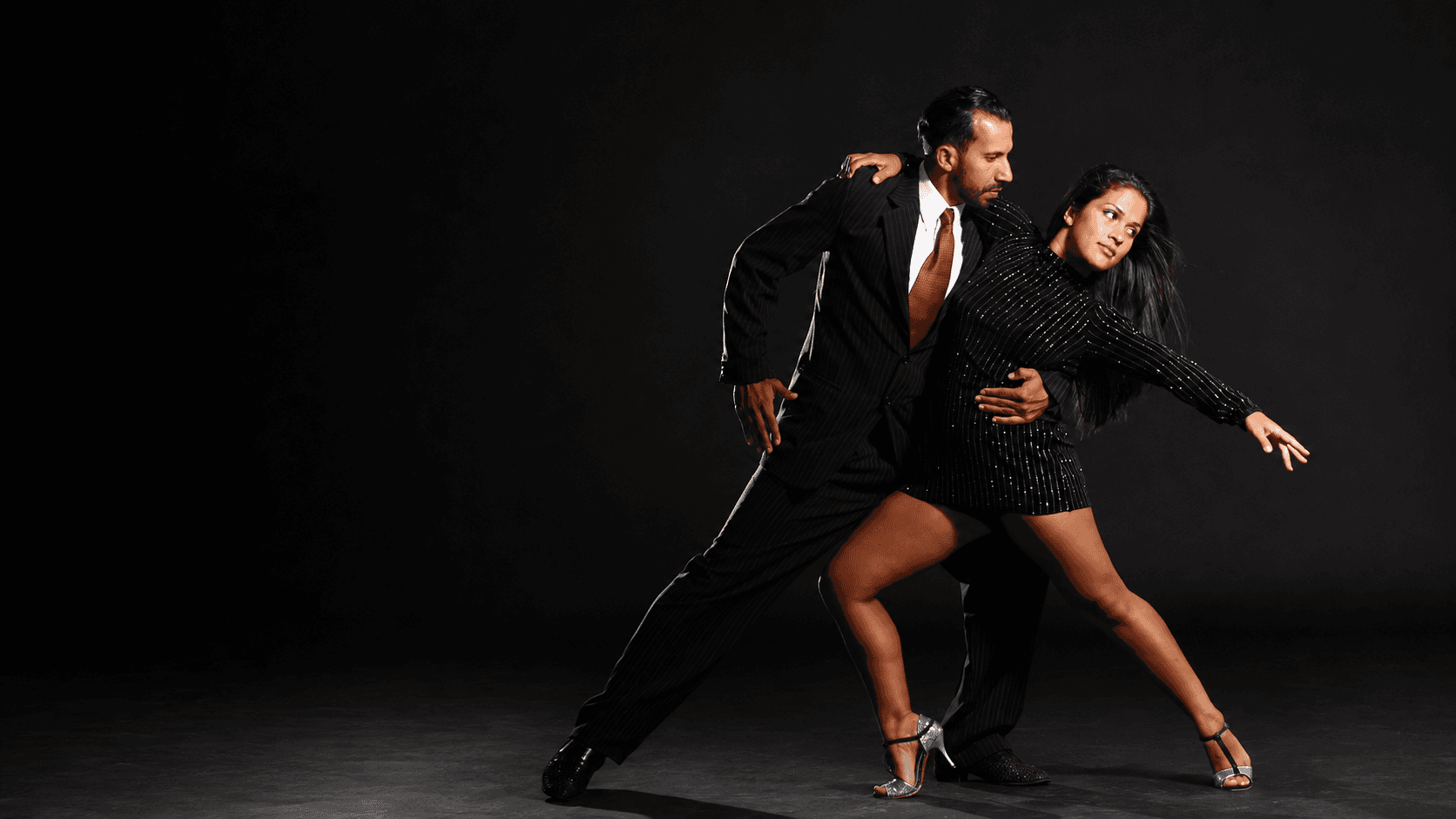 Pareja de tango en estudio, pose dramática con extensión de piernas