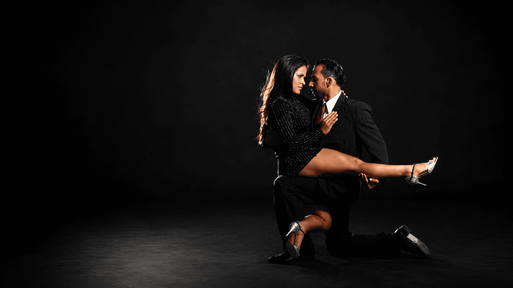 Pareja de tango en un abrazo cercano, mirándose a los ojos