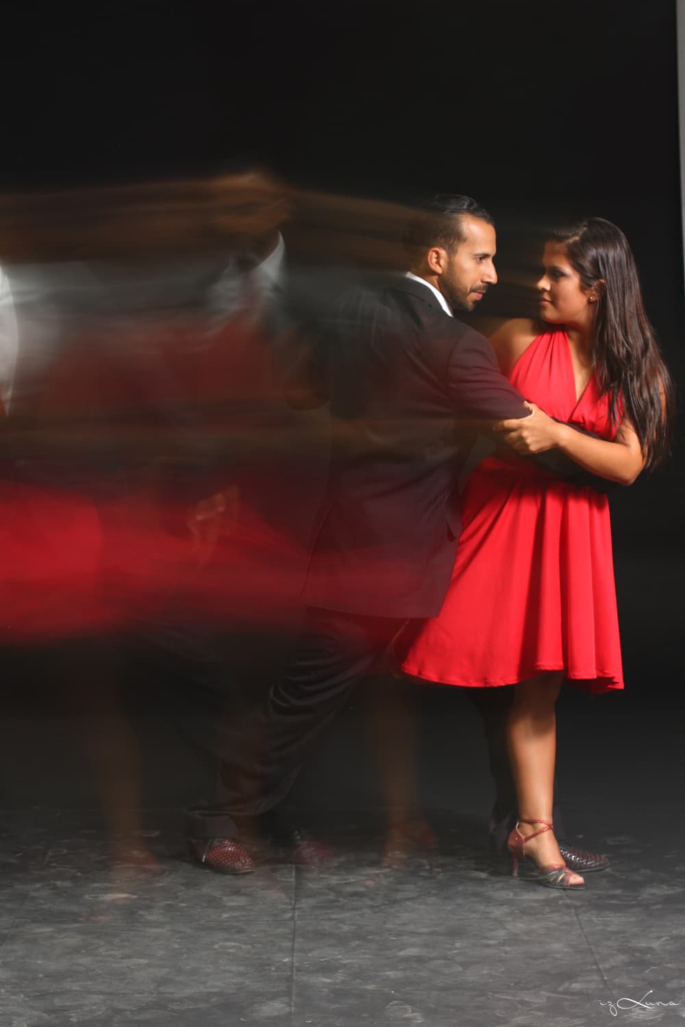 Acompañamiento profesional de tango en una milonga, abrazo cercano con vestido rojo