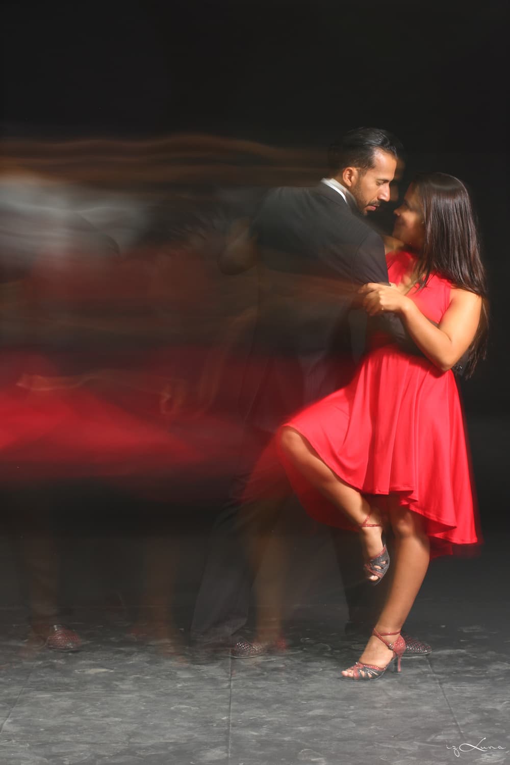 Tango Partner bailando con vestido rojo en una milonga, quiebre en movimiento