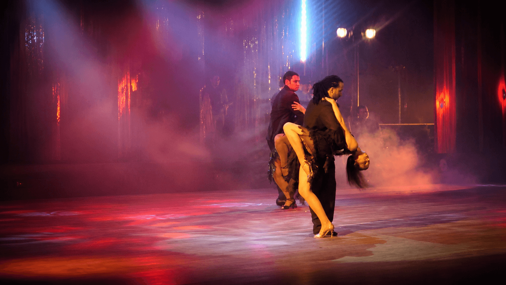 Show de tango en un escenario teatral con niebla y luces de colores